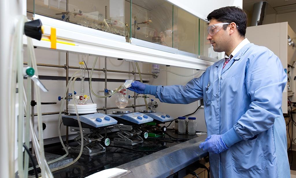a pharmacy student wearing scrubs and safety goggles works in the lab
