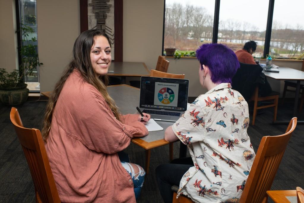 两个学生坐在一张有笔记本电脑的桌子旁学习