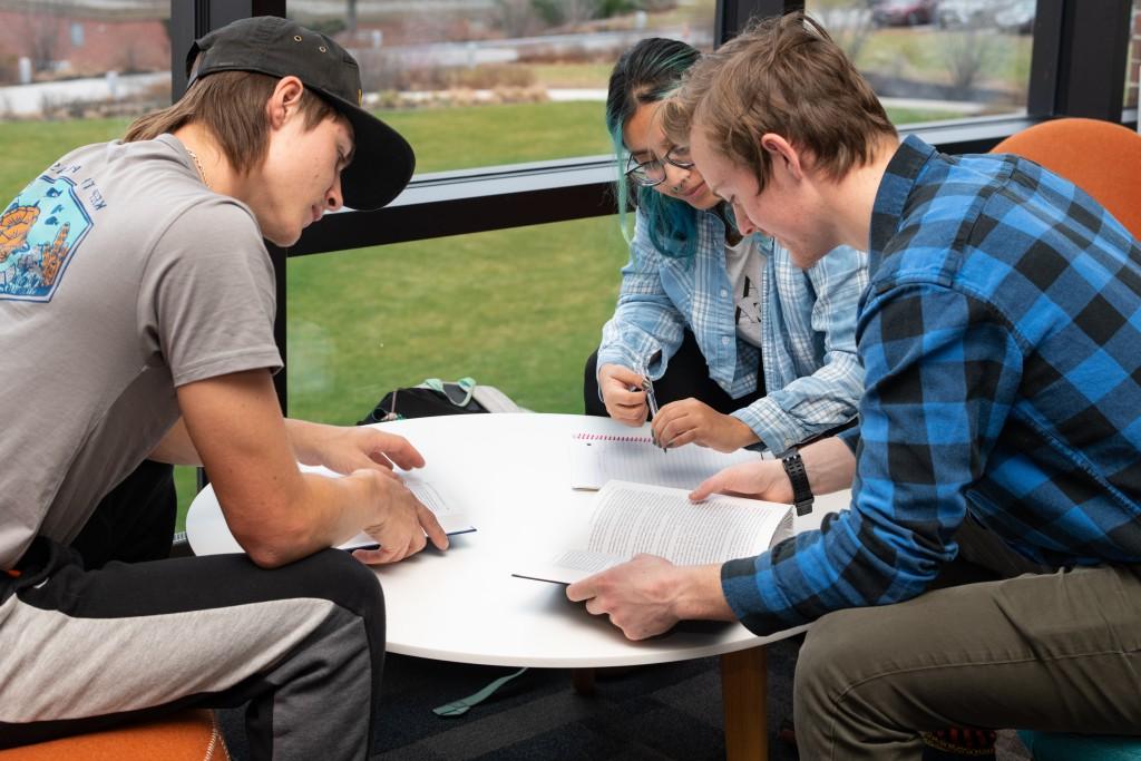 三个东北大学的学生围在一张桌子旁学习笔记
