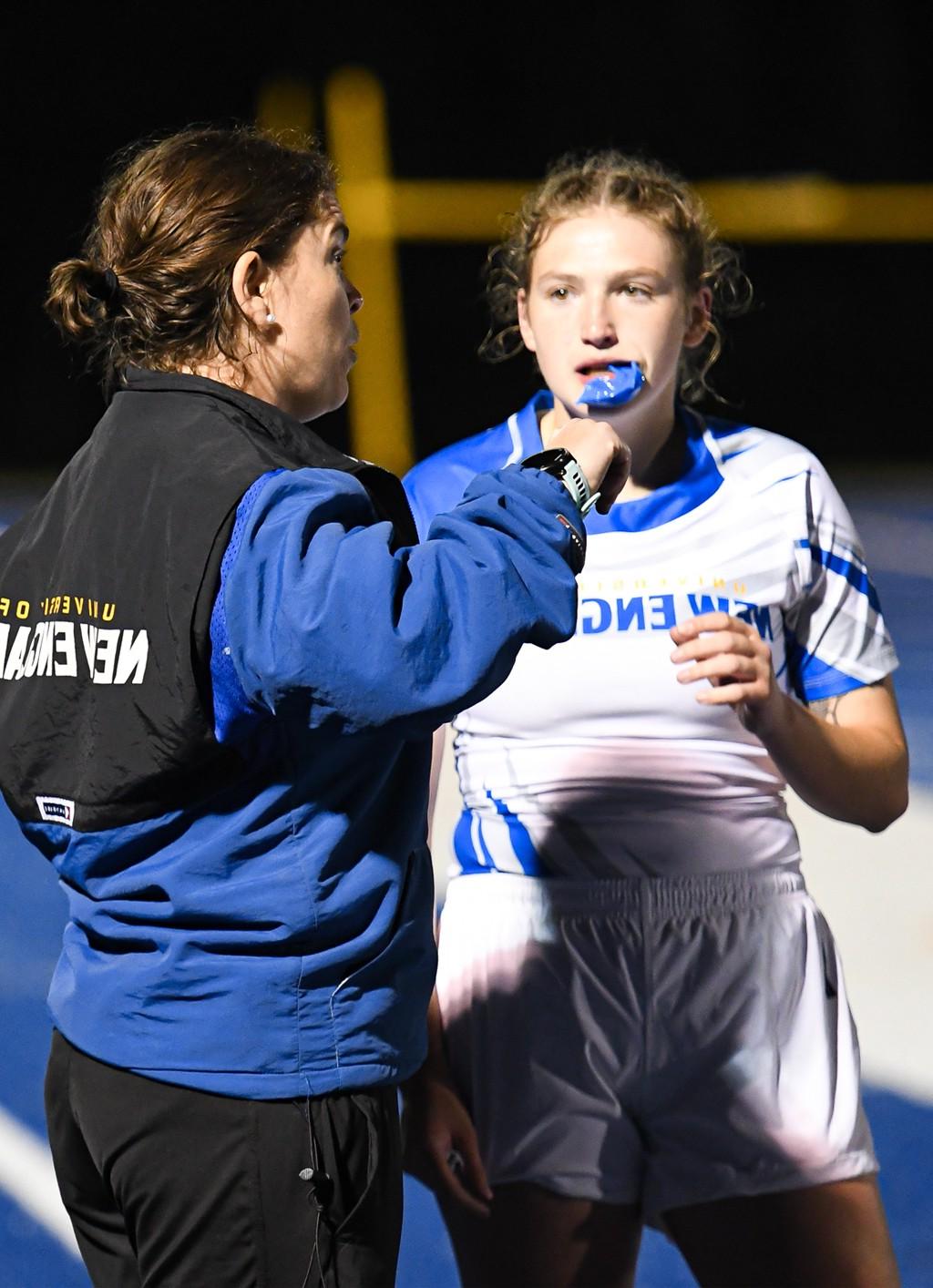 A coach speaks with a field hockey player during a game