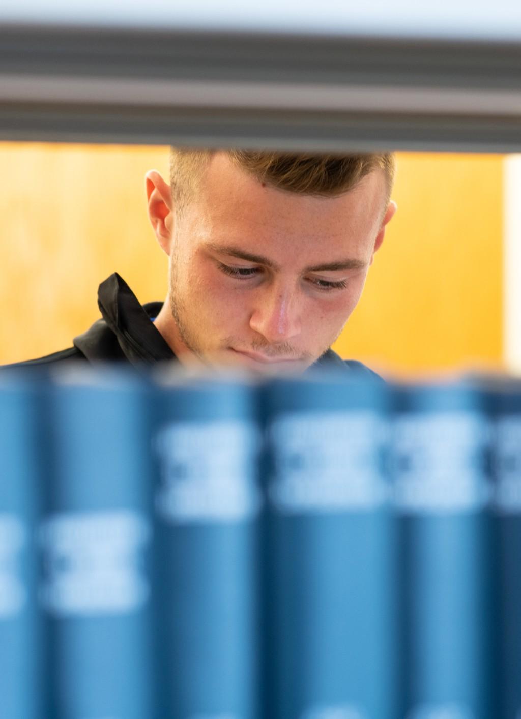 A student stands behind a row of books in the Ketchum Library