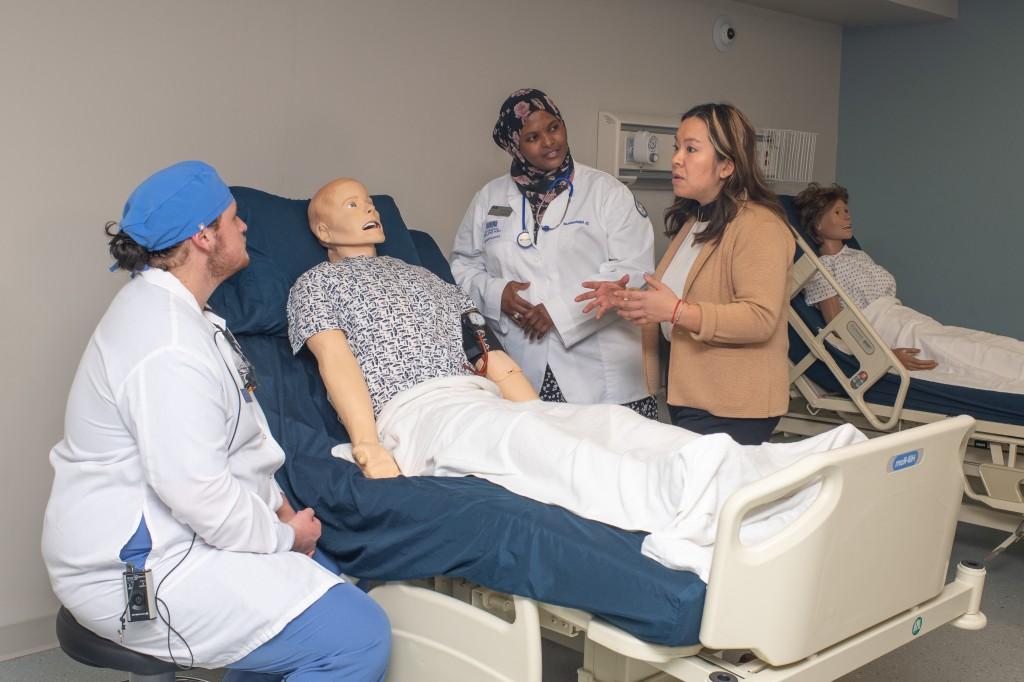 A group of health 学生 discuss treatment for a patient dummy in the Simulation Lab
