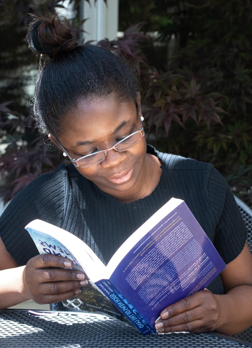 A student sitting outside and reading a class book