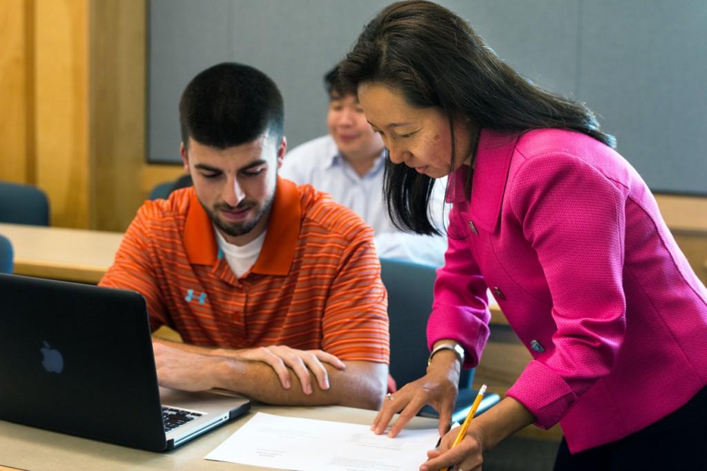 A faculty member looks over paperwork with a student