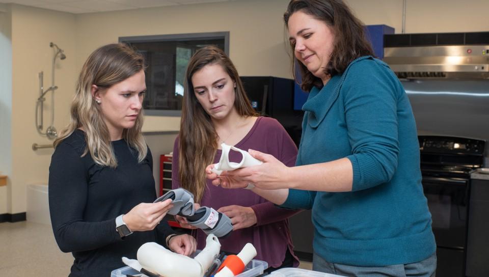 Three Occupational Therapy students standing together looking at various wrist braces