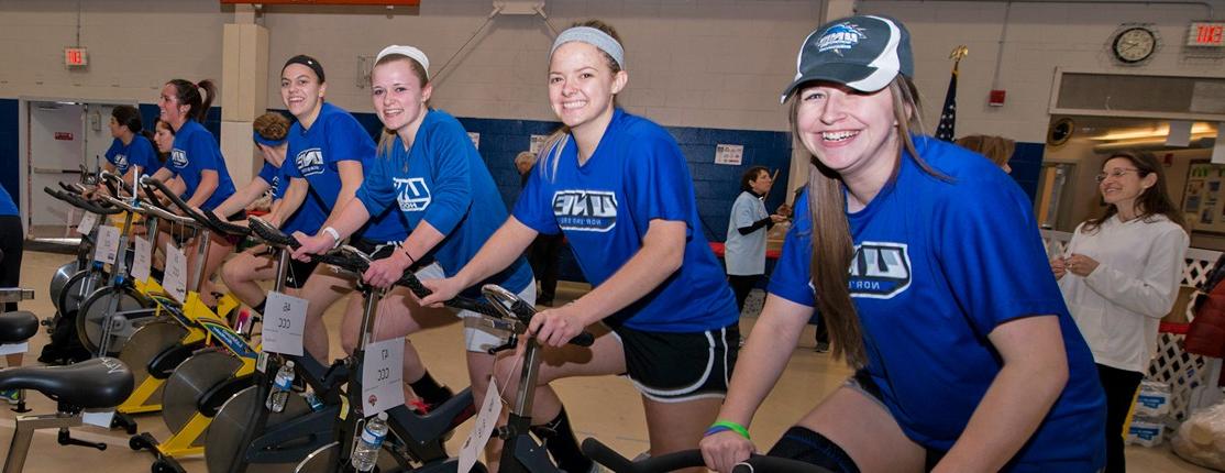 一排学生在“自行车为生命”活动中骑着固定自行车