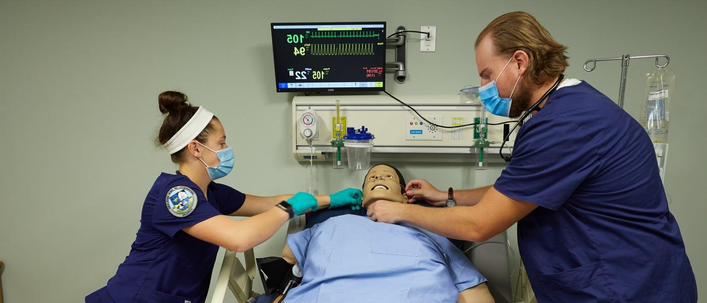 Two nursing students checking vitals on a dummy in the Simulation Lab