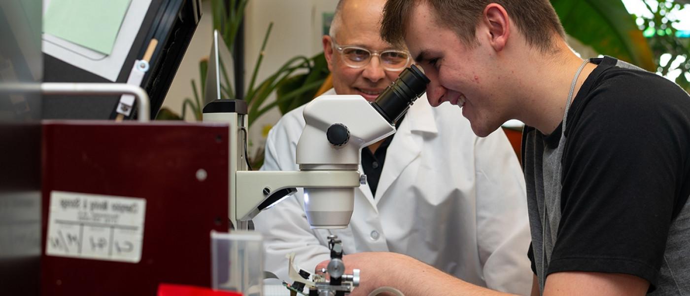 一位教授在帮助学生观察显微镜