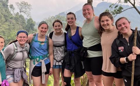 A group of students pose while on a hike in Guatemala; the forest is visible behind them